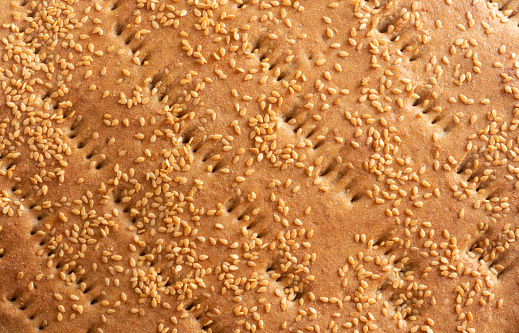 Full frame photo of baked bread as food background. Sesames are seen on top. Shot with a full frame mirrorless camera.