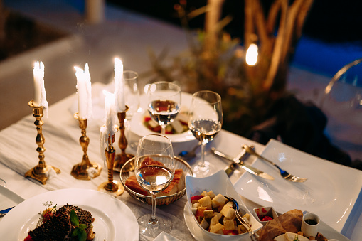 Table with burning candles in candlesticks, glasses and food outside in the evening. High quality photo