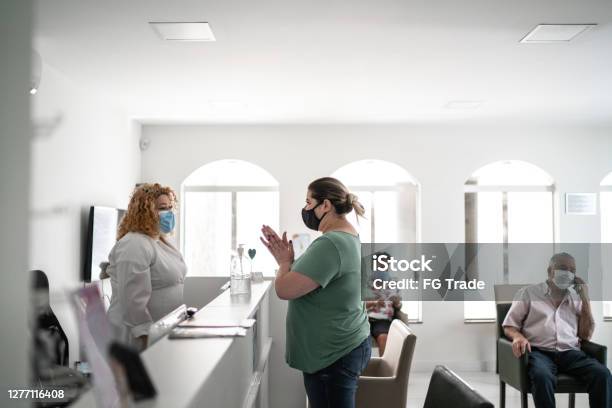 Patient Arriving At Medical Clinic Reception And Using Hand Sanitizer Stock Photo - Download Image Now