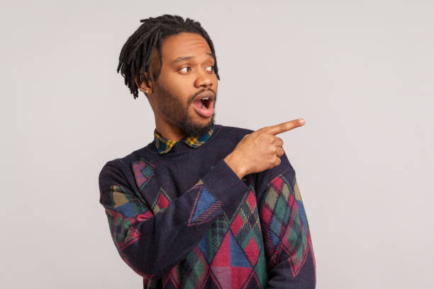 istock Extremely surprised african guy with dreadlocks pointing finger away with big eyes and open mouth, wondered amazed with advertisement, freespace 1277118466