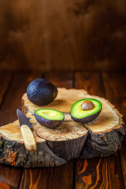 still life with avocado and knife on wooden board, vertical image, negative space