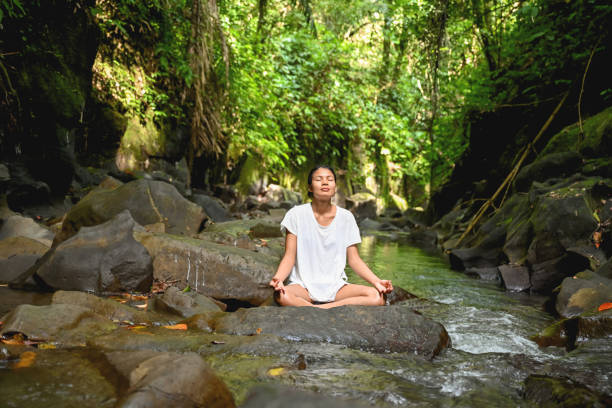 istock Woman meditating sitting on rock 1277120099