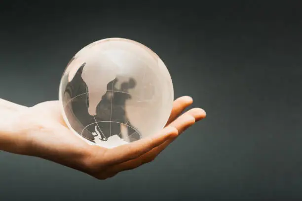 Woman holding a crystal ball etched with a map of the world, South America prominent.