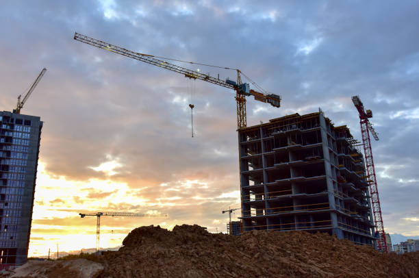 istock Tower cranes in action at construction site on sunset background 1277125020