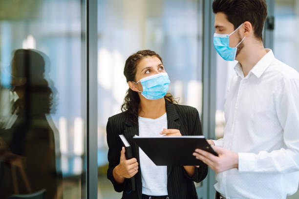 istock Business colleagues wearing medical face mask discussing together work issues at office. 1277125445