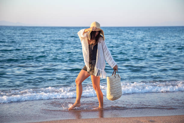 istock Beautiful boho model in a hat with a wicker bag on the beach 1277126506