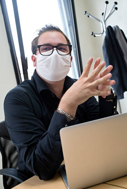 istock A man wears a respiratory mask because of the corona virus is behind his computer explaining something 1277129831
