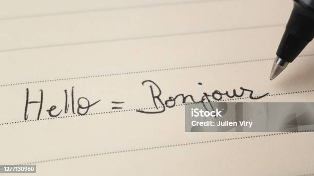 Beginner French Language Learner Writing Hello Word Bonjour For Homework On A Notebook Macro Shot Stock Photo - Download Image Now