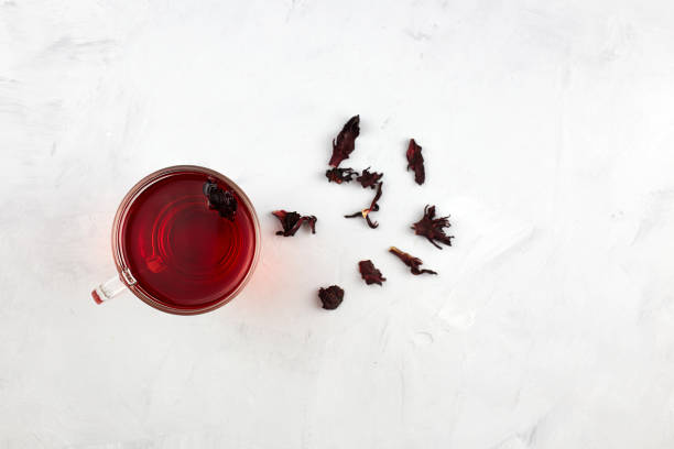 a cup with red hot hibiscus tea or sudanese rose - pink rose flower color image imagens e fotografias de stock