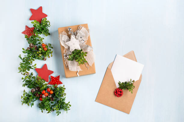 istock Rustic wooden blue background with Christmas gift and empty white card in craft envelope. 1277132375
