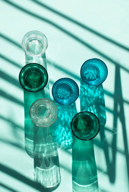 istock Empty glasses on blue mint paper background. Harsh light through glasses, shadows. 1277132392