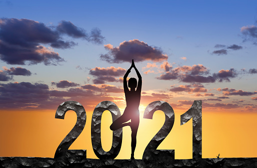 Woman practicing yoga with New Year 2021 at sunset