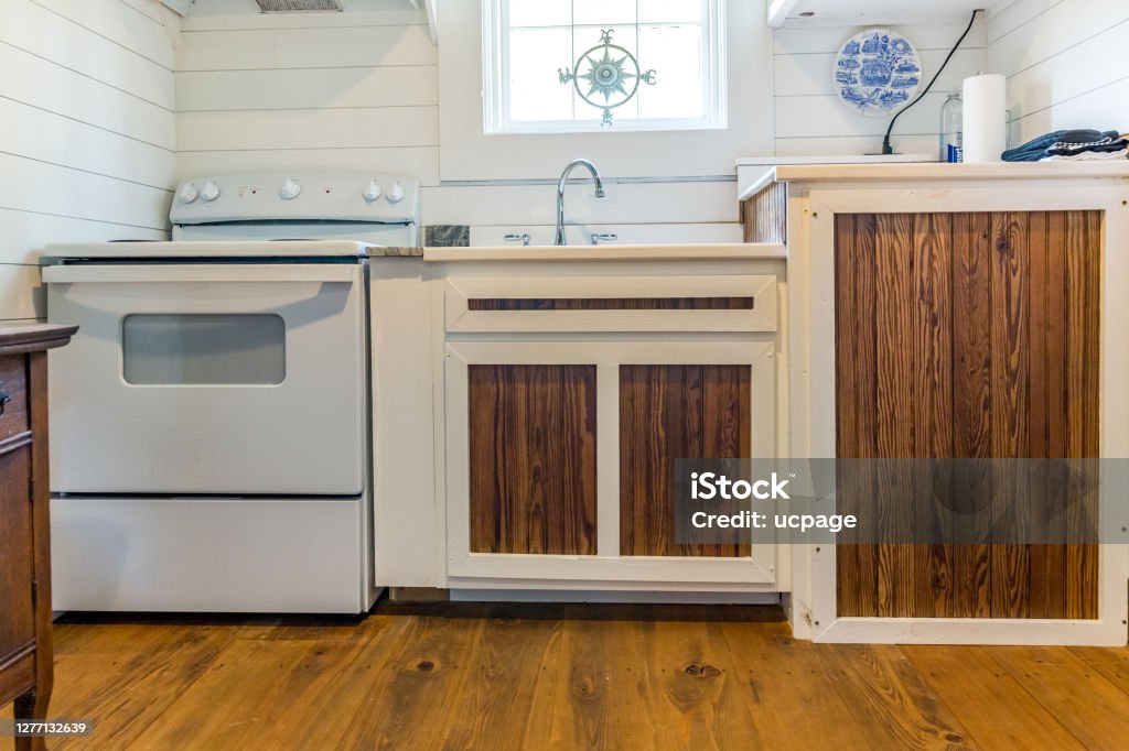 Custom built cabinets with rustic wood paneling inserts in a kitchen in a hunting and fishing cabin Appliance Stock Photo