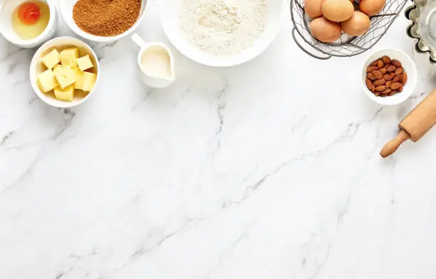 Photo of Baking background with ingredients standing on a marble table surface