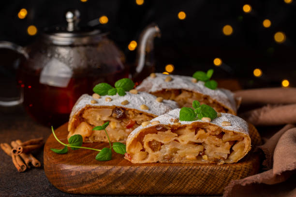 Apple strudel with hot tea. Christmas lights on dark background. Apple strudel with hot tea. Christmas lights on dark background. apple strudel stock pictures, royalty-free photos & images