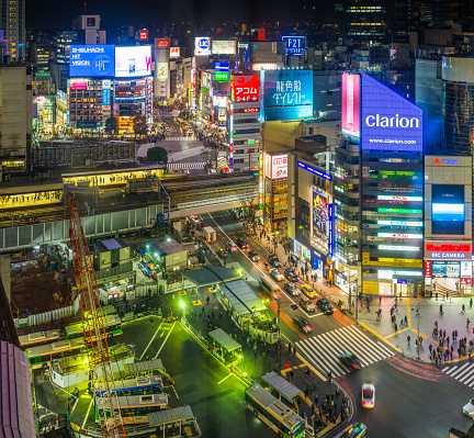 Aerial view over the iconic Shibuya Crossing and the crowds of commuters and shoppers on the streets below the colourful neon signs in the heart of Tokyo, Japan’s vibrant capital city.