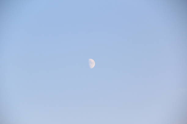 White moon against the blue daytime sky