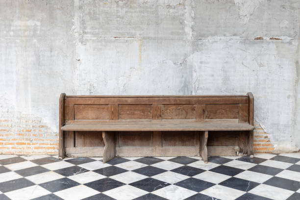 front view of old single wooden bench on checkered pattern marble tiles floor with brick and cement wall background in church - pew imagens e fotografias de stock