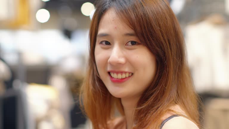 Portrait of a Beautiful Happy Young Asian Teenager woman looking at the camera and smiling with a cheerful and happy expression standing in a shopping store, enjoying on her holiday or weekend.