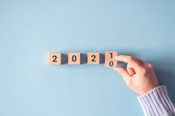 Hand flipping wooden blocks for change year 2020 to 2021 on blue paper background. Hand flipping wooden blocks for change year 2020 to 2021 on blue paper background. New year and holiday concept. gliding photos stock pictures, royalty-free photos & images