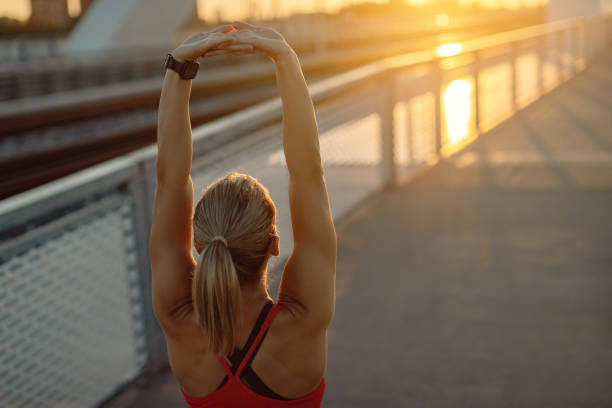 istock Back view of female athlete stretching on a bridge at sunset. 1277140263
