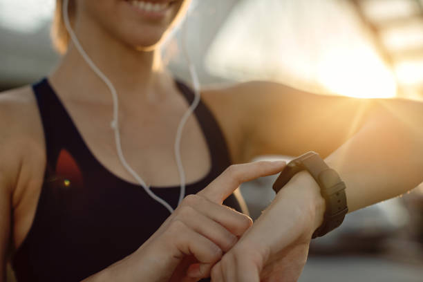 nahaufnahme der athletischen frau mit fitness-tracker bei sonnenuntergang. - fitness tracker stock-fotos und bilder