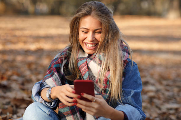 istock Young woman in the park using smartphone and smiling 1277140752
