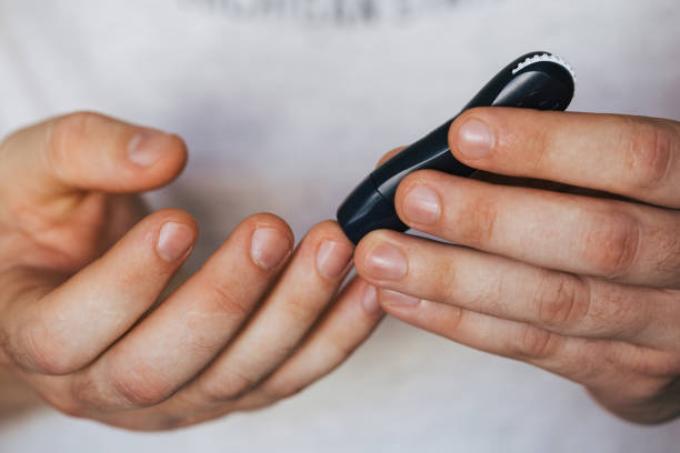 istock Close up of a man's hand using a lancet on his finger to check blood sugar using a glucose meter, using as medicine, diabetes, glycemia, healthcare and people concept. 1277141471