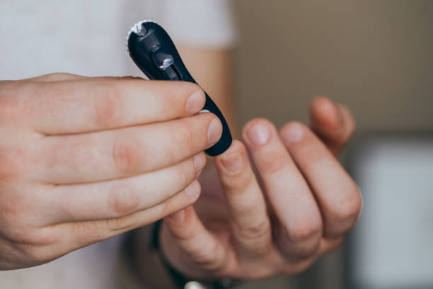 istock Close up of a man's hand using a lancet on his finger to check blood sugar using a glucose meter, using as medicine, diabetes, glycemia, healthcare and people concept. 1277141475