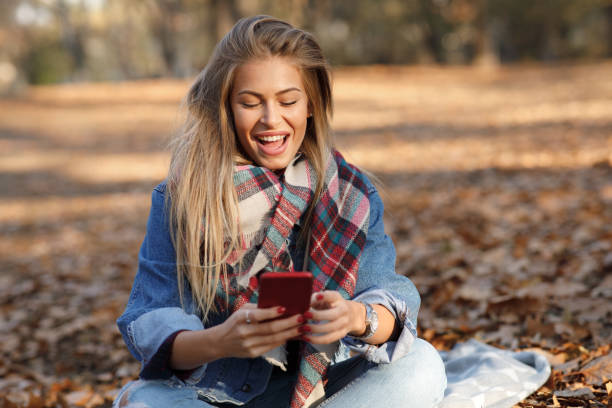 istock Young woman in the park using smartphone and smiling 1277141501