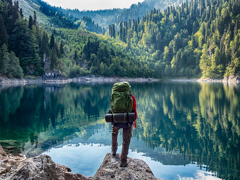 Turista con mochila en el fondo del lago de montaña photo