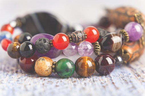 Garnet beads and amethyst, rose quartz and rock crystal crystals on a pink background.