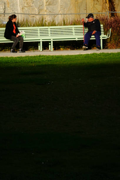 Stockholm, Sweden Sept 28, 2020 A man and woman sit on a bench and  social distance from each other in the setting sun in a park in the  Norra Djurgardsstaden or Stockholm Royal Seaport, urban development.