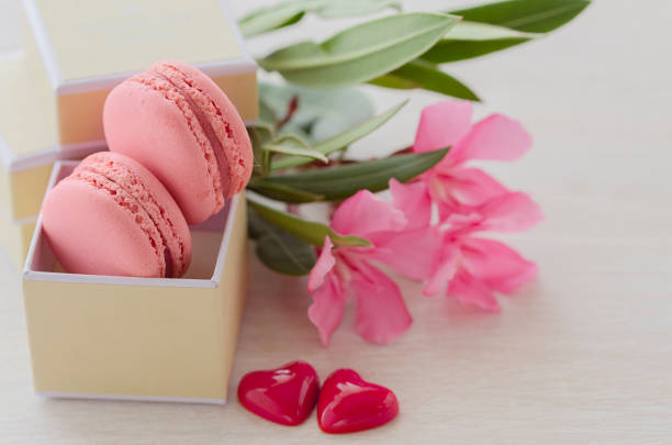 Pink Macaroons in gift box with  flower bouquet and two hearts. Love and Romantic present concept. Saint Valentineâs day celebration card.