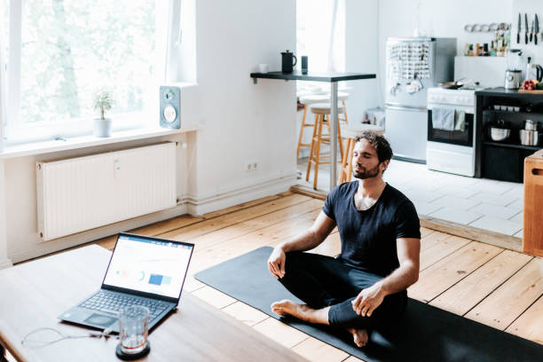 Adult man meditates at home office during a break from working Photo series of an adult man doing a workout at the home office during a lockdown. Shot in Berlin. exercise mat photos stock pictures, royalty-free photos & images
