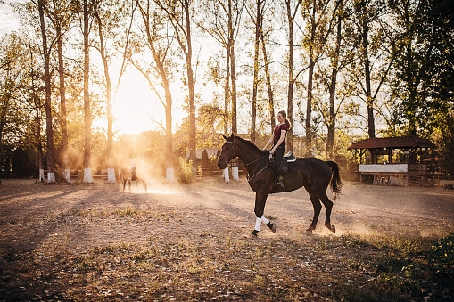 One young girl riding a horse in outdoor equestrian arena.