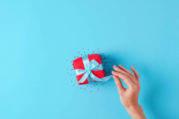 istock Woman hand opens red gift on blue. Colorful Christmas concept. Flat lay, copy space 1277148066