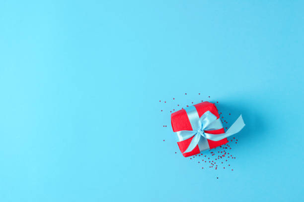 istock Red gift with confetti on blue background. Christmas or holiday concept. Flat lay, copy space 1277148068