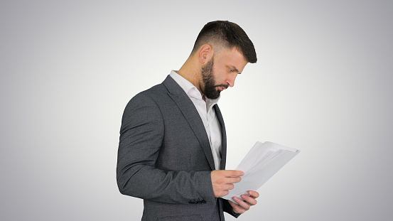 Bottom view young pensive smart employee business man corporate lawyer in black suit shirt tie hold clipboard with papers document prop up chin indoor apartment background. Achievement career concept.
