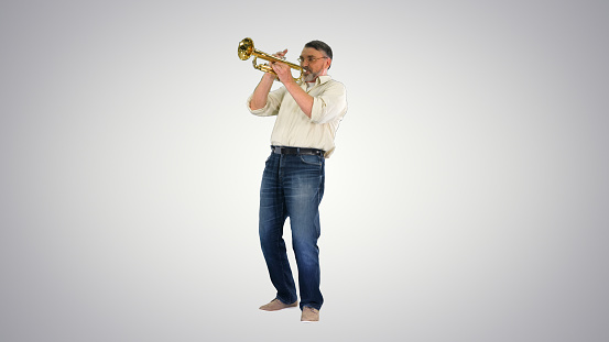 Excited young musician playing trumpet isolated on white background, rear view