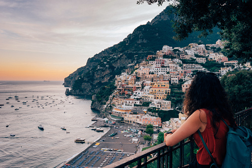 Rear view of a young woman admiring sunset in Positano, Amalfi Coast, Italy.
