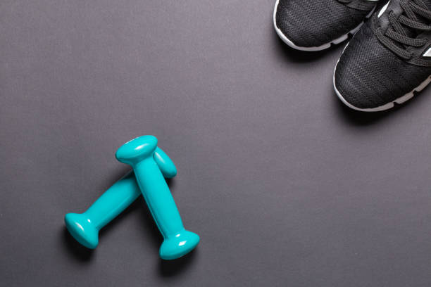 istock Black sneakers and turquoise dumbbells with a white sole on a black background 1277150147