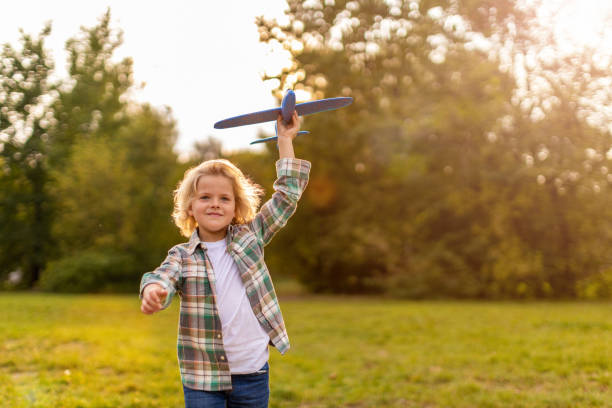 istock Little boy playing with toy plane in park 1277151531
