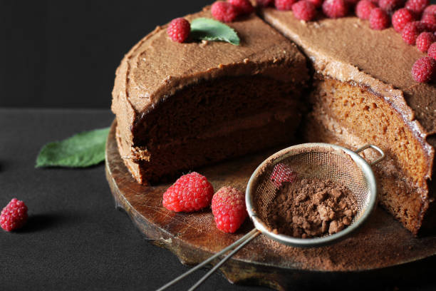 istock Chocolate cake with raspberries. Cake on a dark background. Sieve with cocoa powder. 1277151834