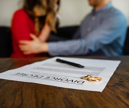Divorce decree document. Man calms down a woman on the background.