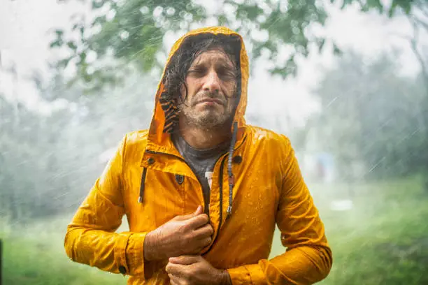 Man with raincoat under heavy rain