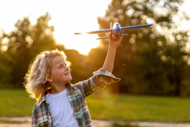 istock Little boy playing with toy plane in park 1277153088