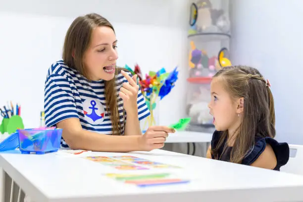 Children speech therapy concept. Preschooler practicing correct pronunciation with a female speech therapist.