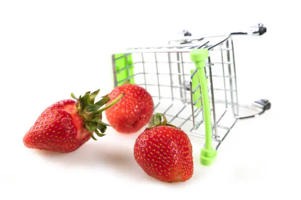 Mini supermarket trolley with scattered strawberries.Fruit sale concept.