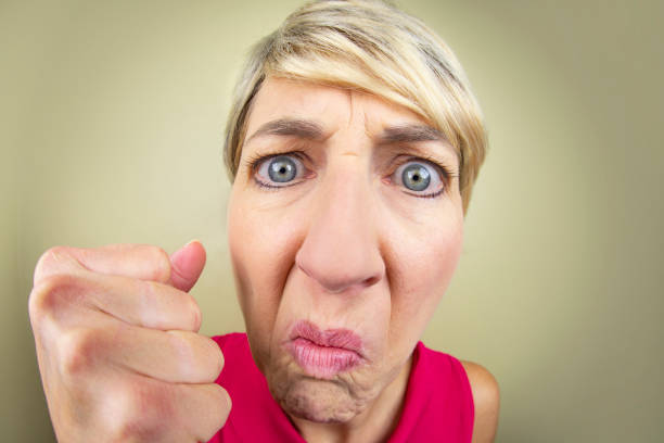 Fisheye Angry Karen Woman A humorous fisheye image of a an angry woman showing her fist. frowning headshot close up studio shot stock pictures, royalty-free photos & images